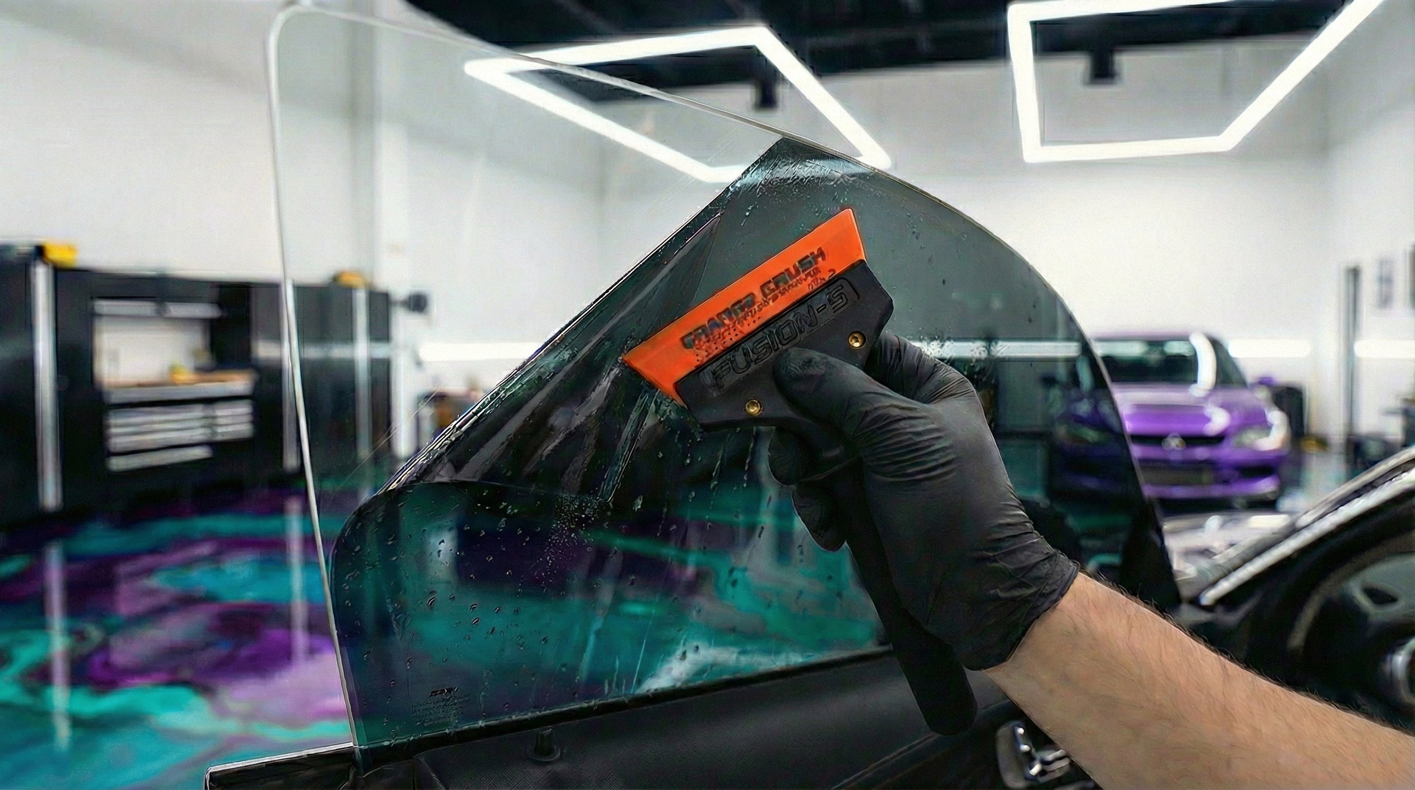 XPEL ceramic window tint installation — professional squeegee application on vehicle glass at DrivenMN detailing shop in Minneapolis, MN